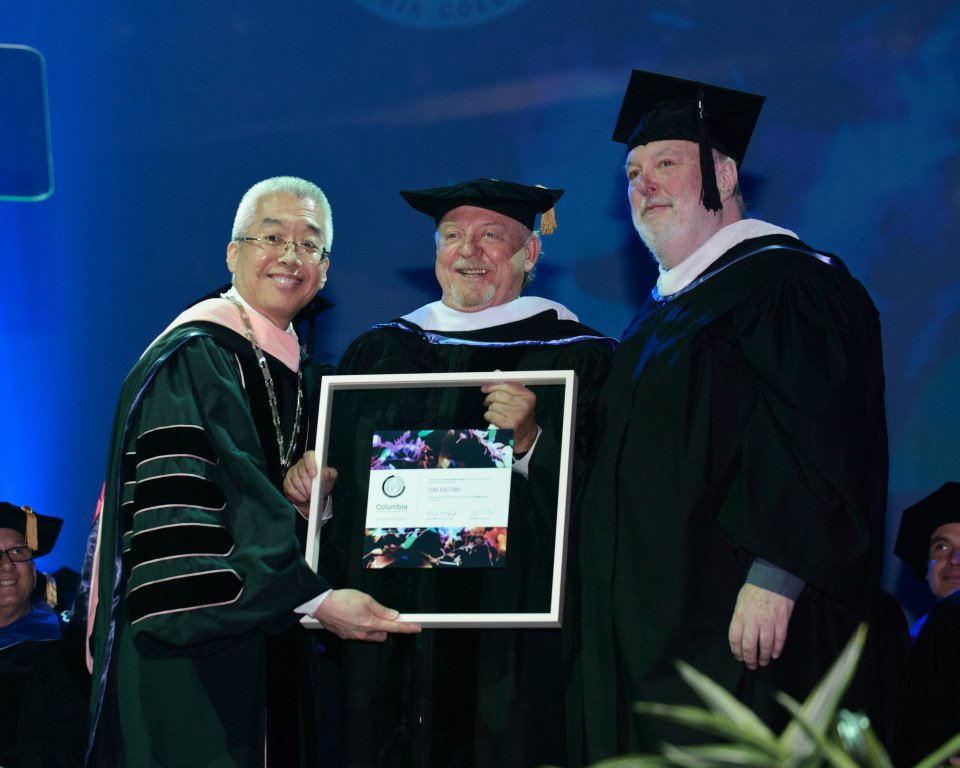 "Grease" coauthor Jim Jacobs (center) received an honorary doctorate from Columbia College Chicago in 2014. Jacobs also spoke at the commencement ceremony for Theatre majors at the historic Chicago Theatre. From left: Columbia College Chicago president Dr. Kwang-Wu Kim, Jim Jacobs, and Theatre Department faculty member Albert WIlliams.